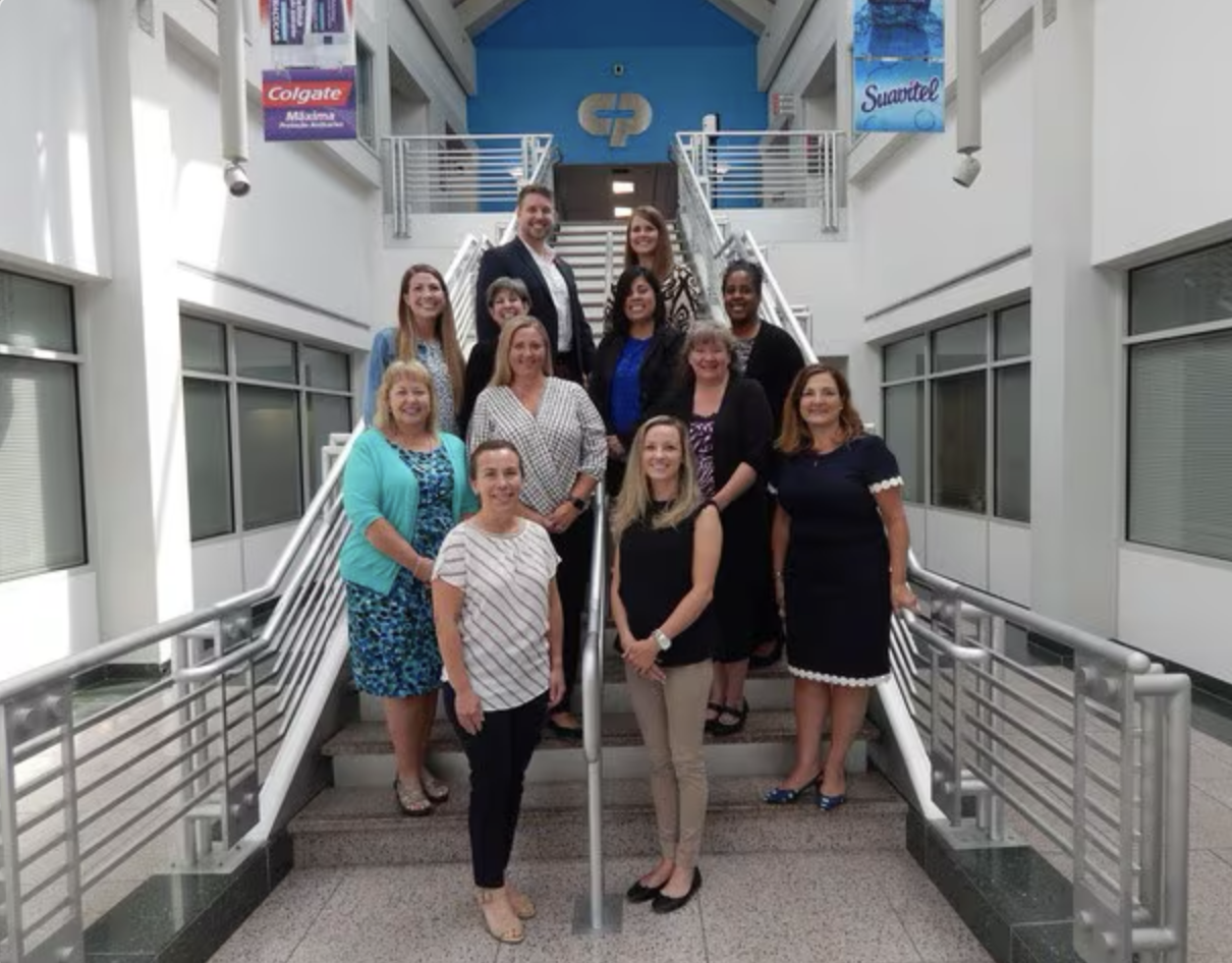 Group of people standing on stairs with Colgate logo visible in the background
